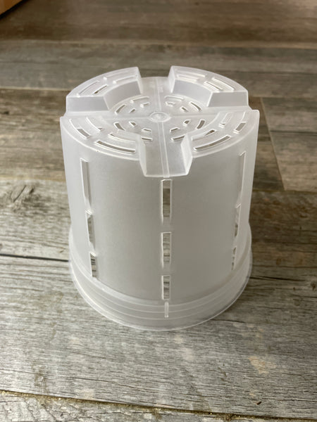 an upside down 6" round transparent orchid flower pot showing the slots on the side, the mesh on the bottom and the raised feet.