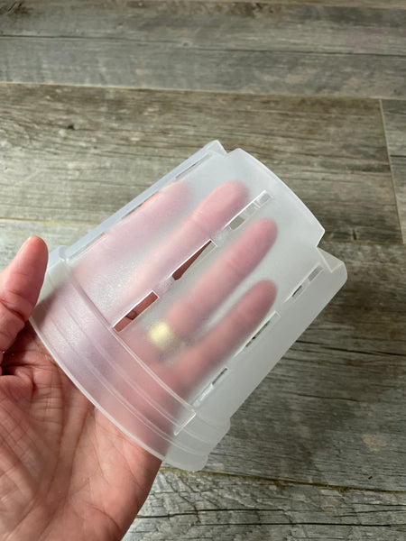 fingers inside a 6" round plastic orchid pot showing the transparency of the pot