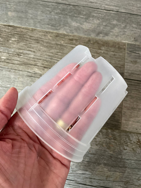 fingers inside a 5" round orchid pot with side slots, showing the transparency of the pot