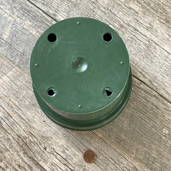 The bottom of a 6" round green plastic bulb pan for use in orchid growing