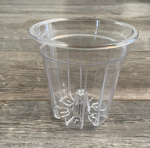 a small clear plastic flower pot  with a wooden background