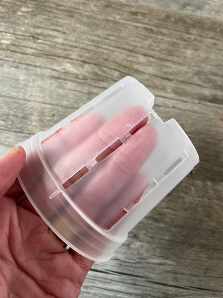 fingers inside a 4" clear round orchid pot with side slots, showing the transparency of the pot