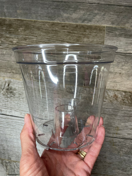 hand holding a spectacularly clear round 5.7" orchid pot with large aeration cone in the bottom of the pot