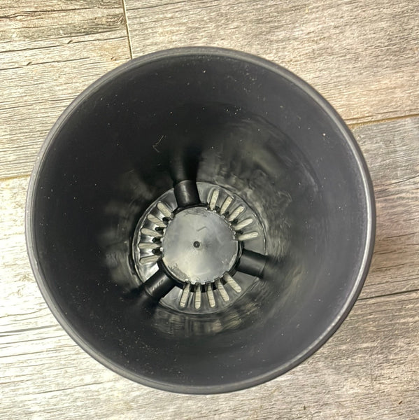 top view of round black plastic flower pot showing the bottom holes