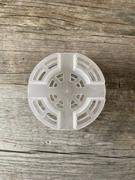 a view of the bottom of a 4" clear round orchid pot showing the many drainage holes